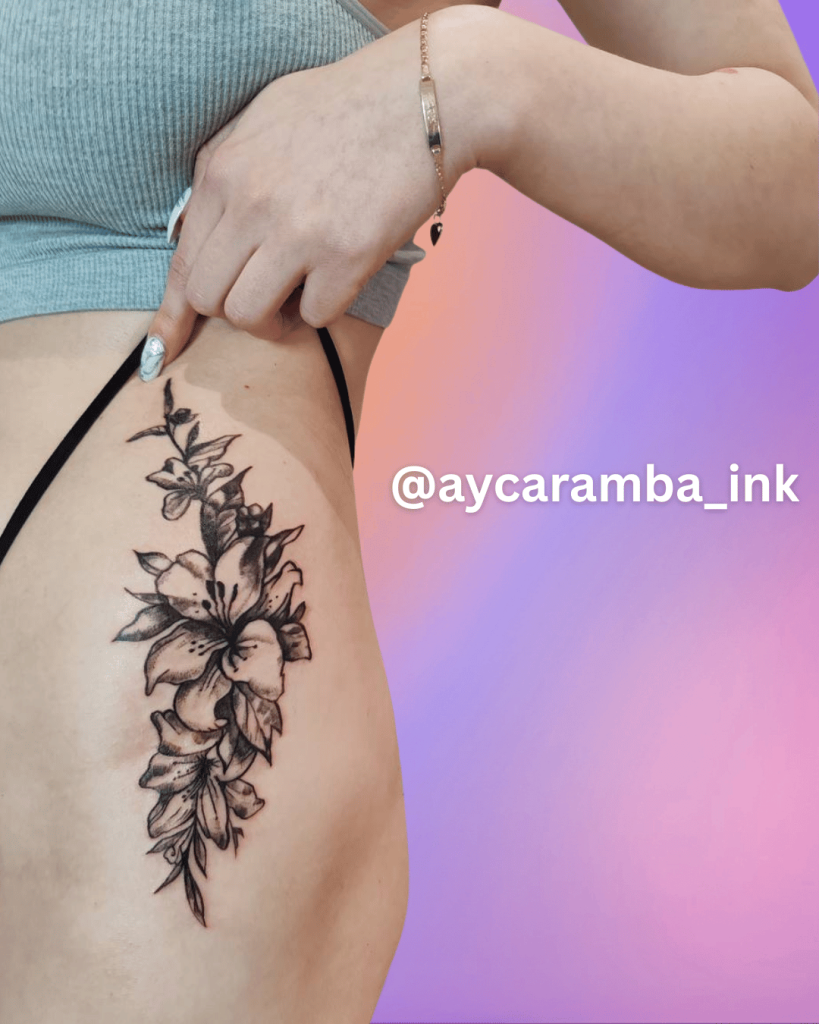 Black and grey floral side tattoo featuring detailed lily flowers and leaves on female ribcage
